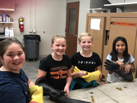 Four students trying on safety gloves.