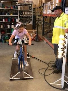 A student riding a bicycle to power lights.