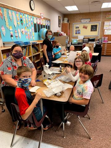 Parents helping the third graders build their houses